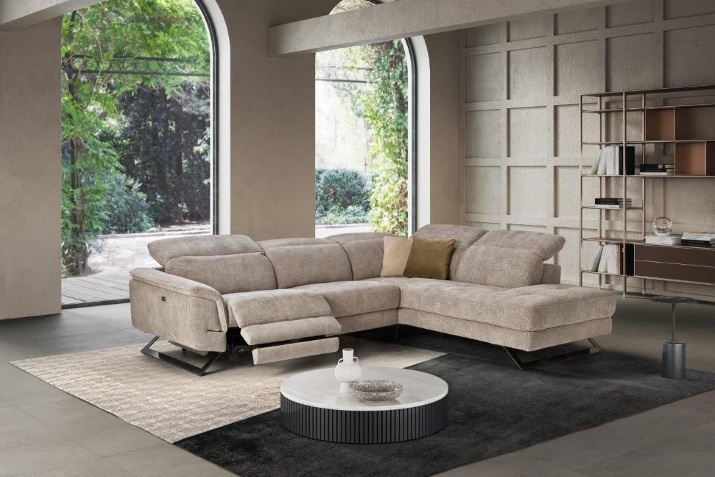 Divano componibile beige in un soggiorno moderno con una grande finestra che si affaccia sul verde.