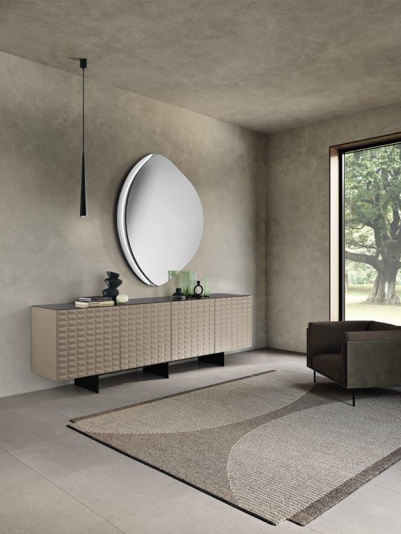Soggiorno moderno con credenza testurizzata, grande specchio ovale e tappeto geometrico.