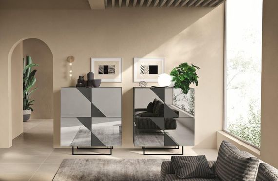 Due mobili moderni con motivi geometrici in una stanza beige con una finestra e un divano.