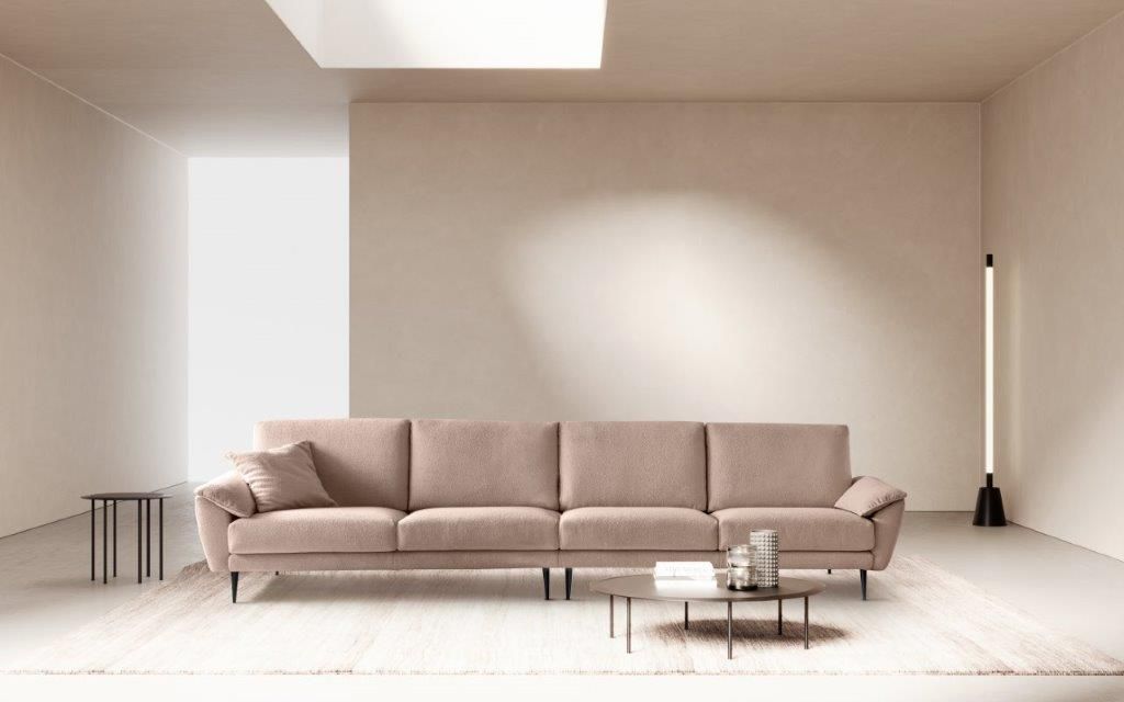 Divano beige in un moderno soggiorno minimalista con tappeto, tavolino e lampada da terra.