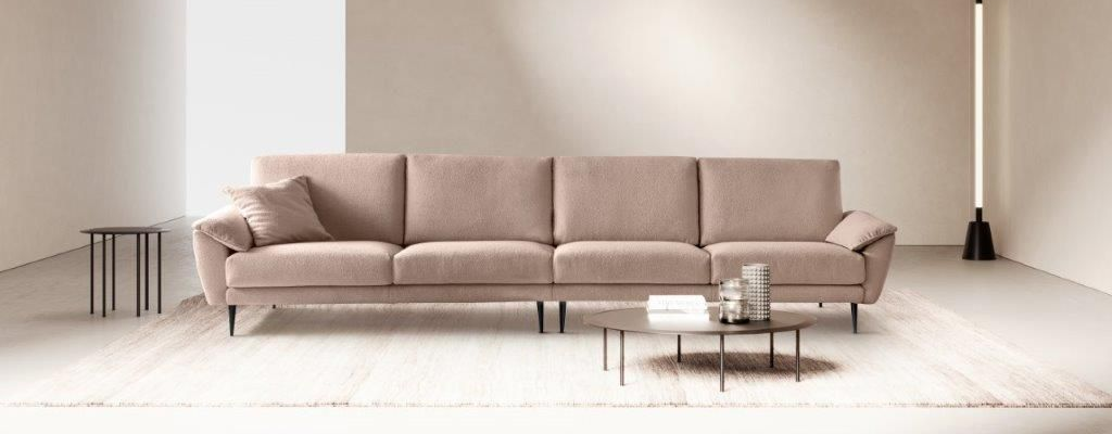 Un soggiorno moderno con un lungo divano rosa, un tavolino da caffè e una lampada alta.