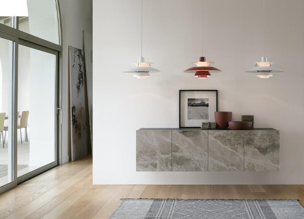 Soggiorno moderno con mobile in pietra galleggiante, lampade a sospensione e grande porta a vetri.