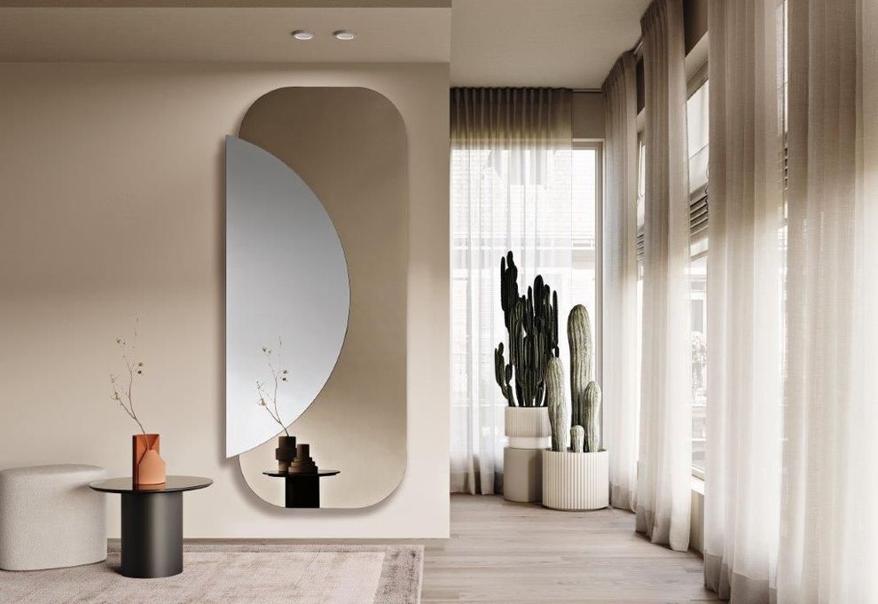 Stanza con grande specchio, cactus e tende trasparenti. Palette di colori neutri: beige, bianco e marrone.