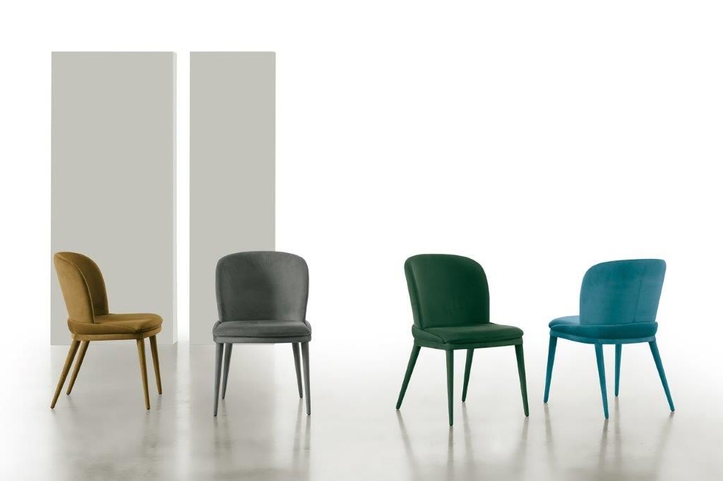 Quattro moderne sedie da pranzo imbottite in diversi colori su sfondo bianco.