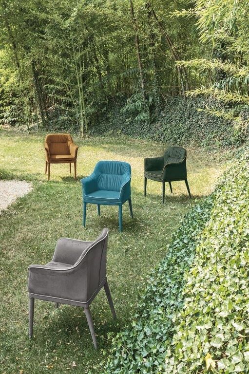 Quattro poltrone imbottite su uno spazio erboso, ciascuna con una diversa tonalità di gioiello, con uno sfondo di alberi.