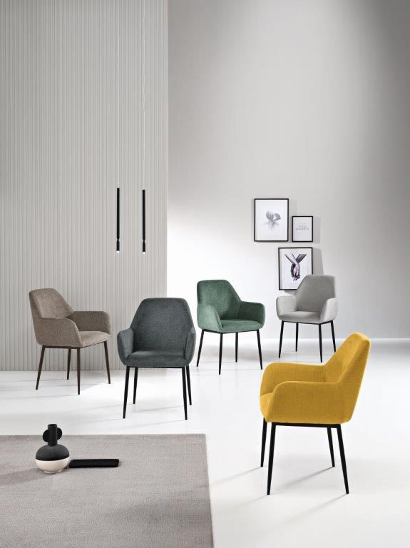 Cinque poltrone imbottite in vari colori con gambe nere in un ambiente luminoso.