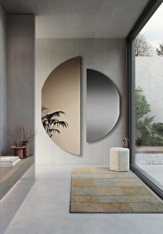 Ingresso elegante con un grande specchio semicircolare e un piccolo tappeto fantasia.