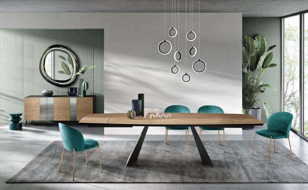 Sala da pranzo con tavolo in legno, sedie color verde acqua e lampada moderna.