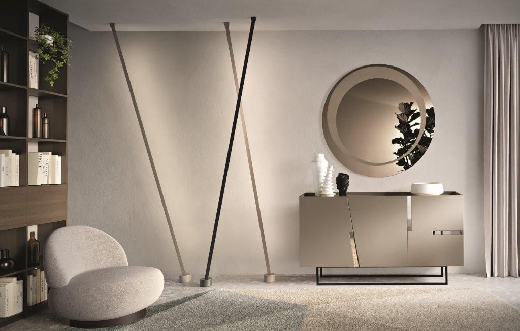 Soggiorno moderno con colori neutri, una sedia curva, un tavolo consolle e un grande specchio rotondo.