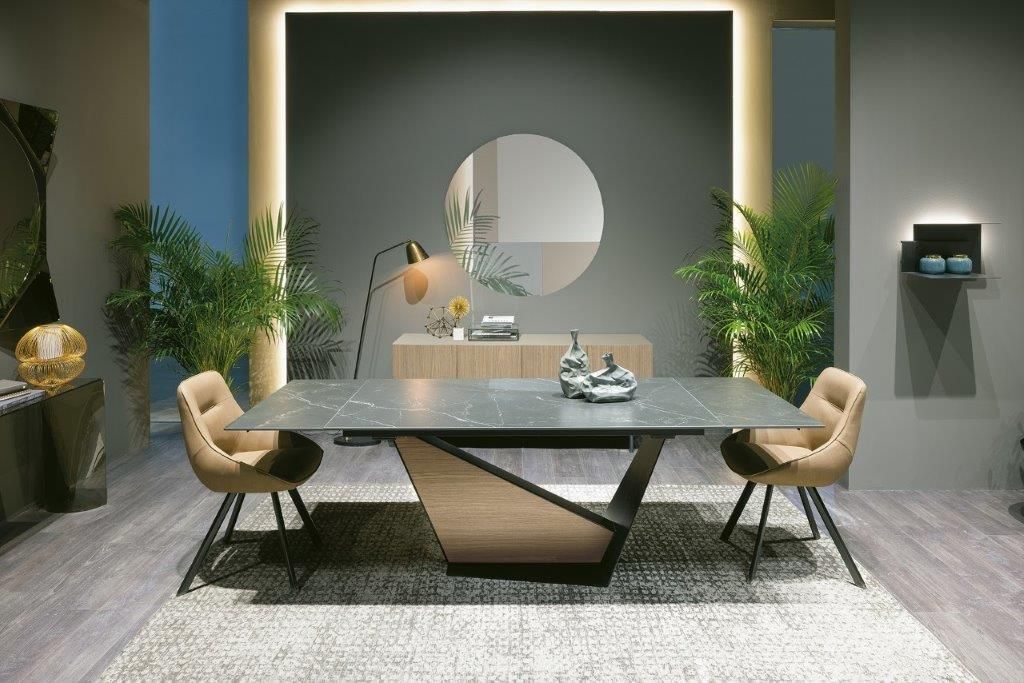 Moderna sala da pranzo con tavolo in pietra, sedie, piante e uno specchio rotondo sulla parete.