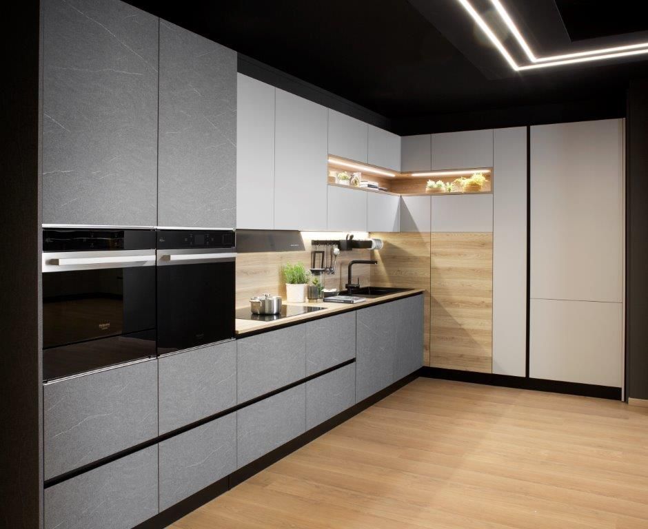 Cucina moderna con mobili grigi, elettrodomestici neri e dettagli in legno.