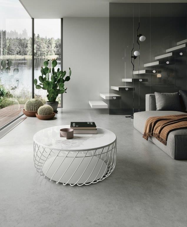 Soggiorno moderno con tavolino in marmo, scala minimalista e vista sul lago.