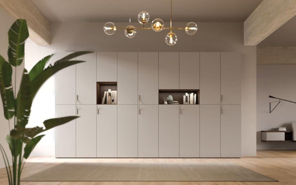 Stanza moderna con mobili contenitori grigio chiaro, due scaffali aperti, una pianta e un lampadario.