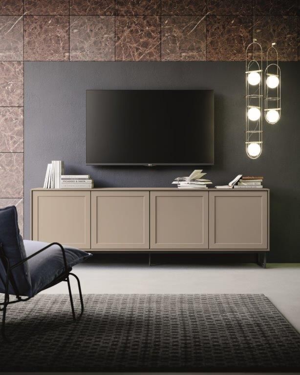 Soggiorno con TV a parete, mobile color marrone chiaro, poltrona blu, tappeto grigio e luci decorative sospese.