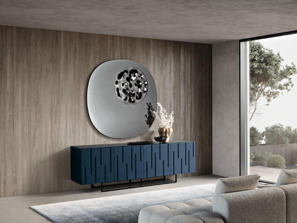Credenza blu con design strutturato, grande specchio rotondo, parete e tappeto dai toni neutri.