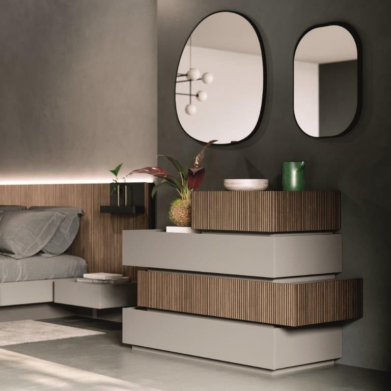 Camera da letto con moderna cassettiera grigia e in legno, due specchi e decorazioni vegetali.