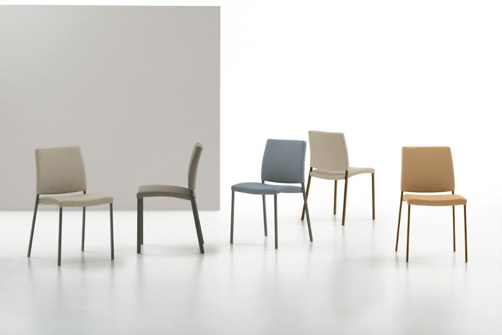 Cinque sedie moderne, di vari colori, su uno sfondo bianco e grigio.
