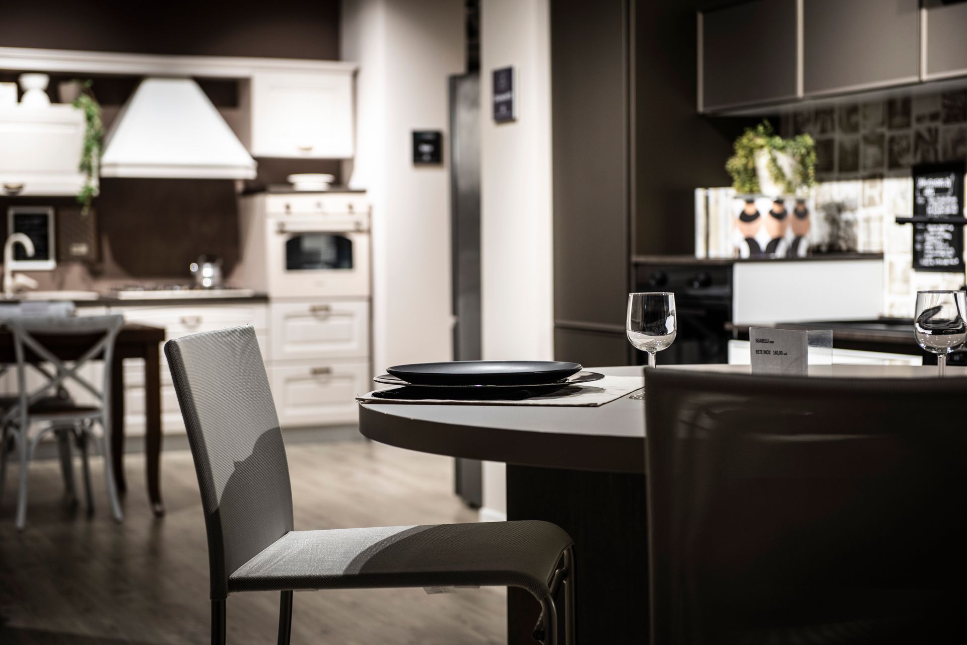 Interno di una cucina moderna con tavolo rotondo, sedie ed elettrodomestici.