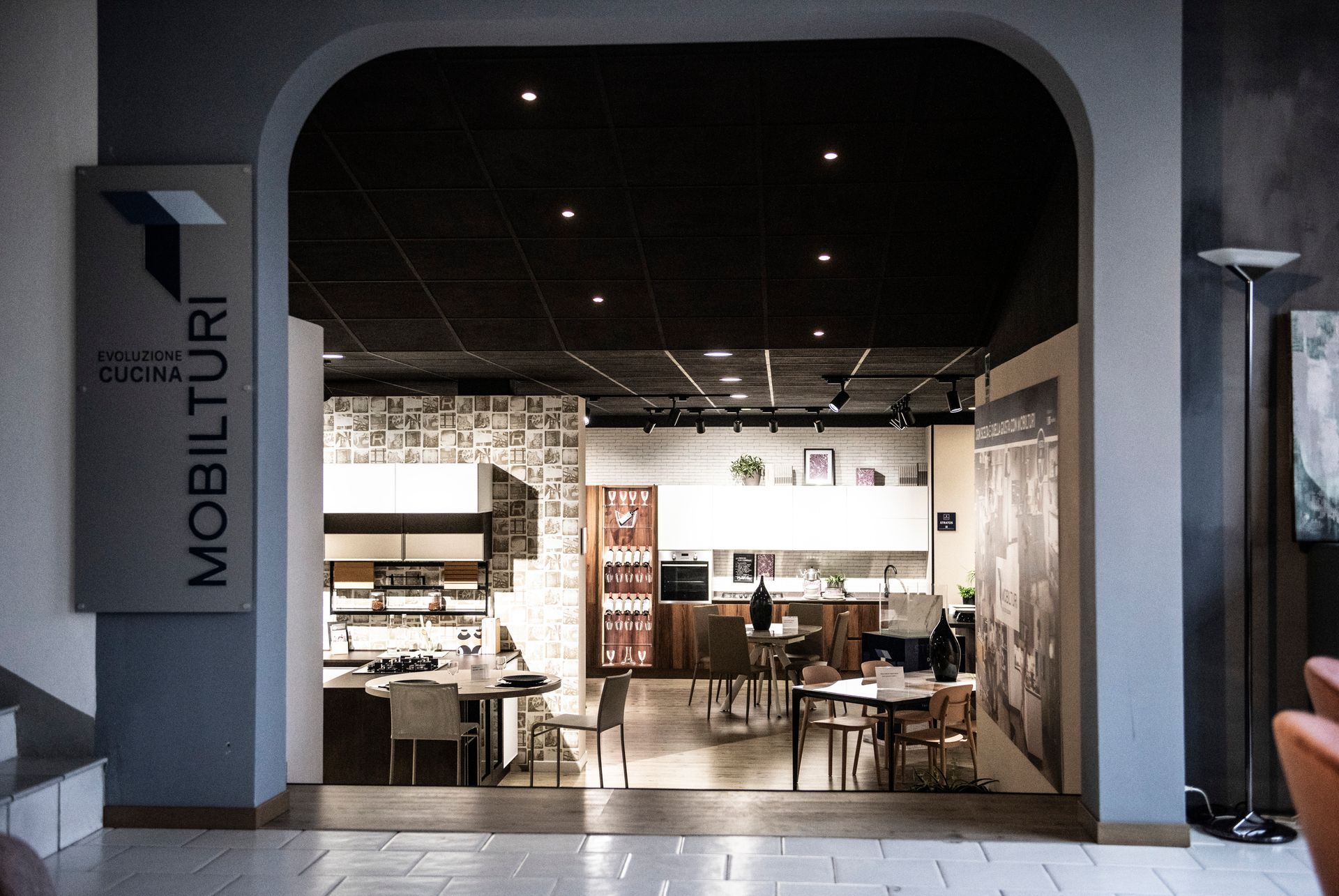 Interno di uno showroom di mobili con cucine e sale da pranzo. Palette di colori grigio, bianco e nero.