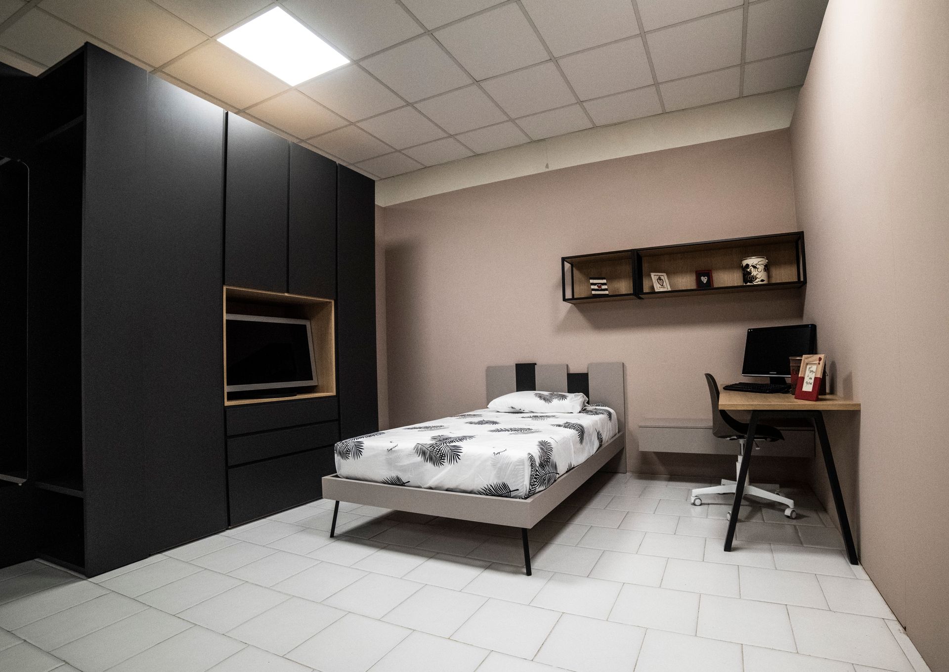 Camera da letto moderna con armadio nero, letto, scrivania e pareti neutre.