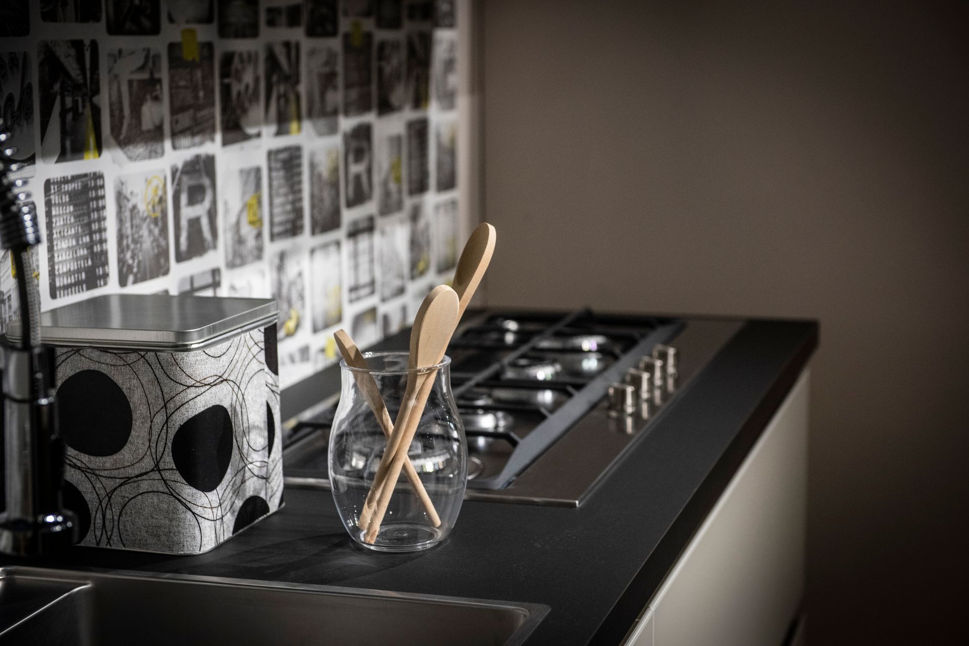 Piano di lavoro della cucina con piano cottura, utensili in un barattolo di vetro e un tostapane decorato.