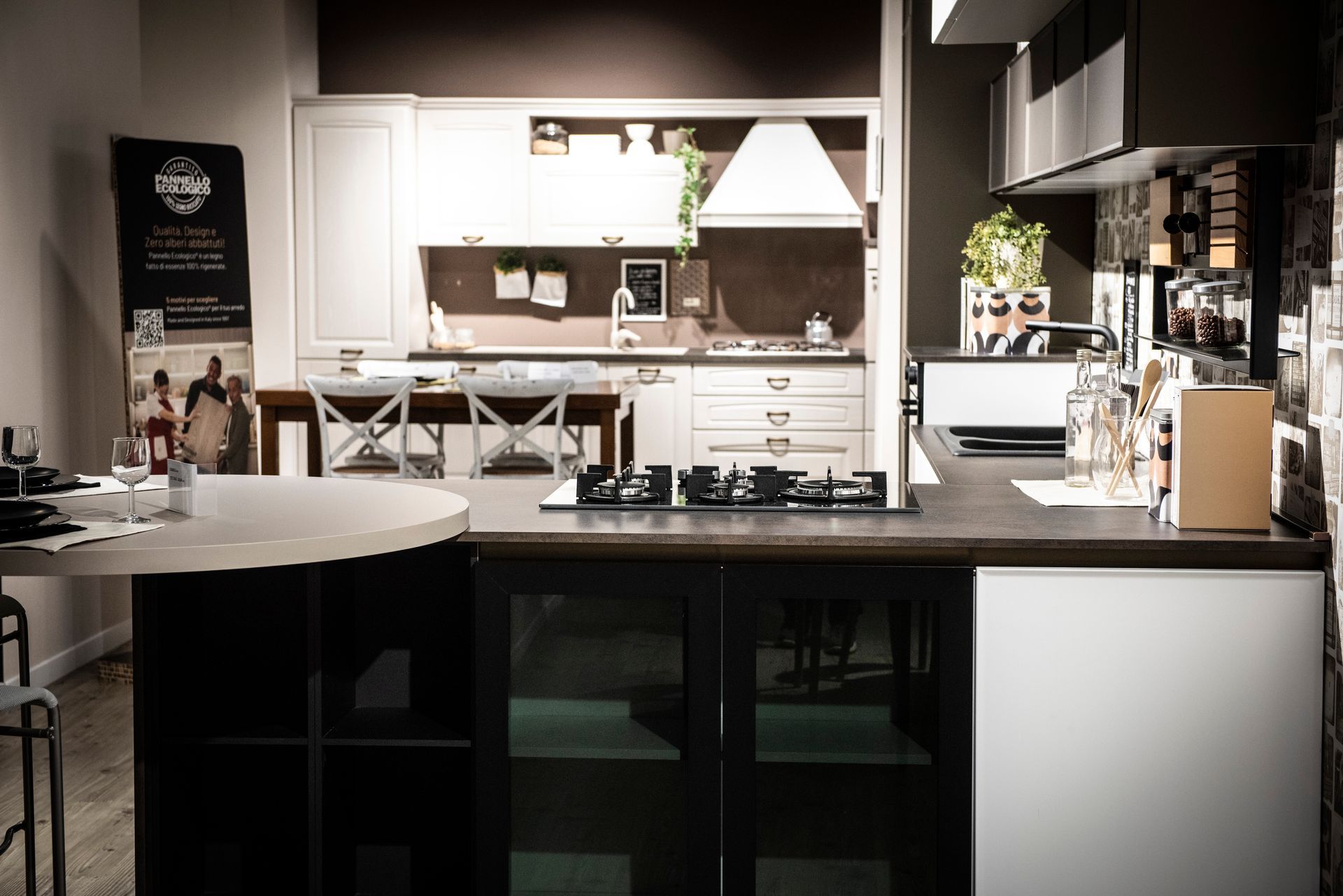 Cucina con isola, pensili e piano cottura. I colori sono bianco, nero e marrone.