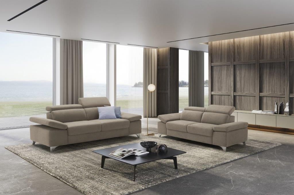 Soggiorno con divani beige, tappeto, tavolino da caffè e ampie finestre.