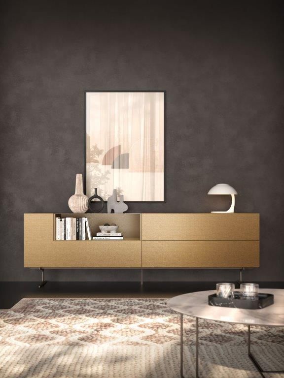 Credenza in legno con decorazioni, opere d'arte e lampada di fronte a una parete scura.