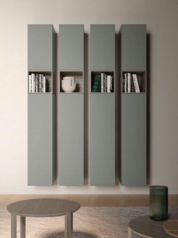 Quattro alti mobili a parete color verde salvia con ripiani rettangolari aperti contenenti libri e un vaso