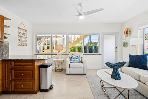 A living room with a couch , chair , coffee table and ceiling fan.