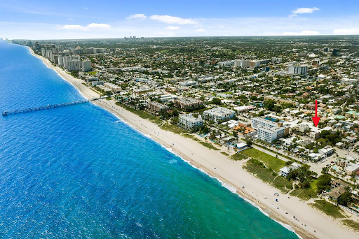 An aerial view of a beach with a red arrow pointing to a house.