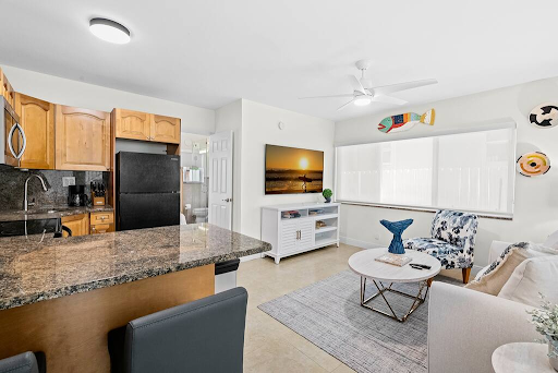 A living room with a couch , table , chairs and a kitchen.