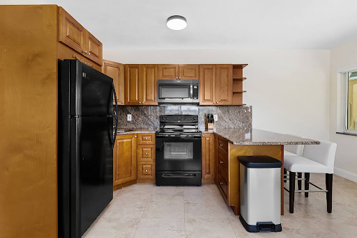 A kitchen with wooden cabinets and a black refrigerator
