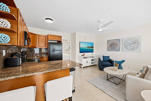 A living room and kitchen in a house with a ceiling fan.