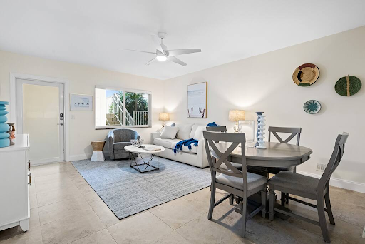 A living room with a couch , table , chairs and a ceiling fan.