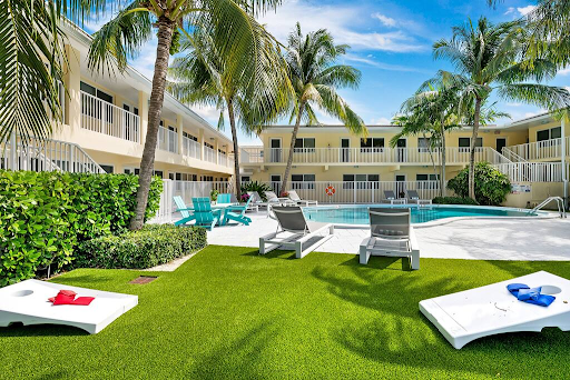 A hotel with a swimming pool and lawn games in front of it.