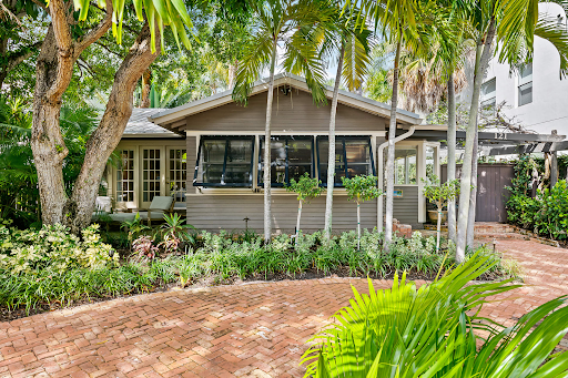 A house with a brick driveway and trees in front of it.