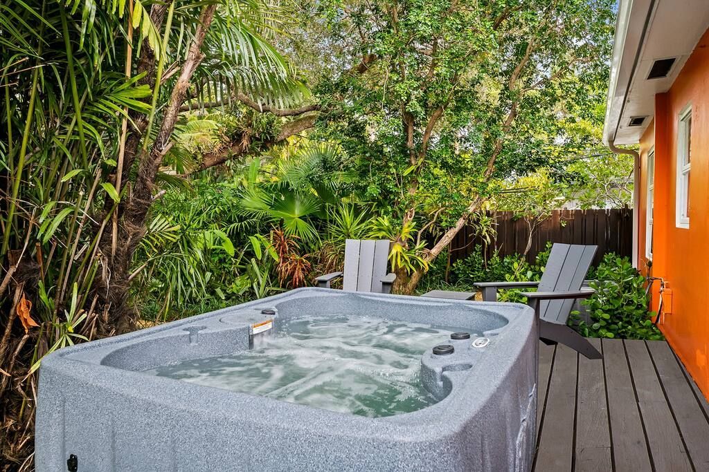 A hot tub is sitting on a wooden deck in the backyard of a house.