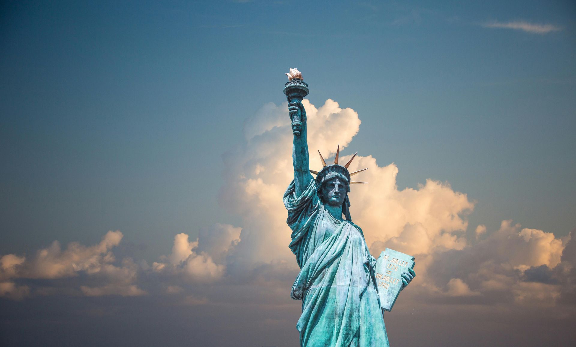Statue of Liberty against a cloudy sky, holding a torch.