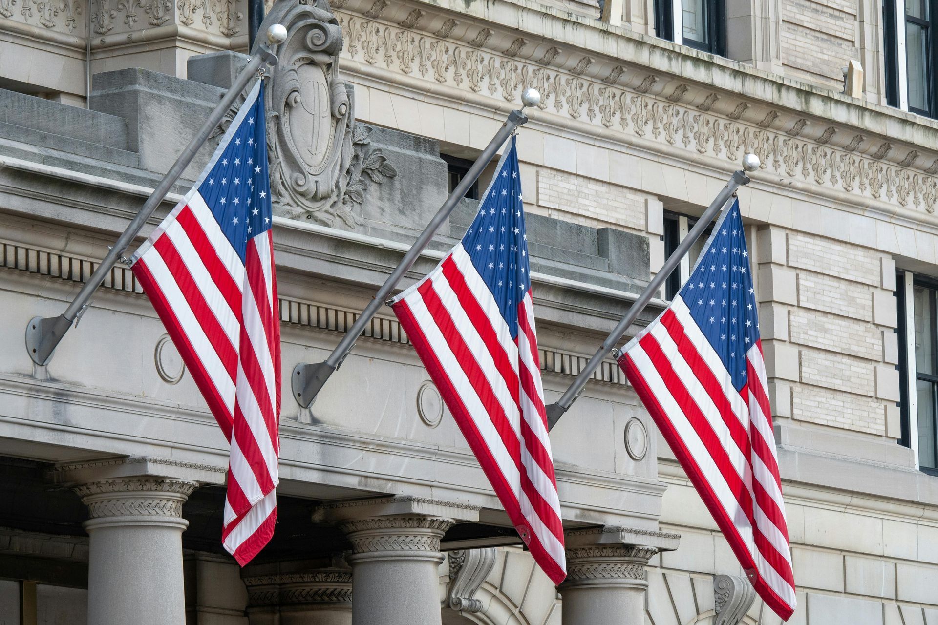 Three American flags on building facade, displaying red and white stripes and blue stars.