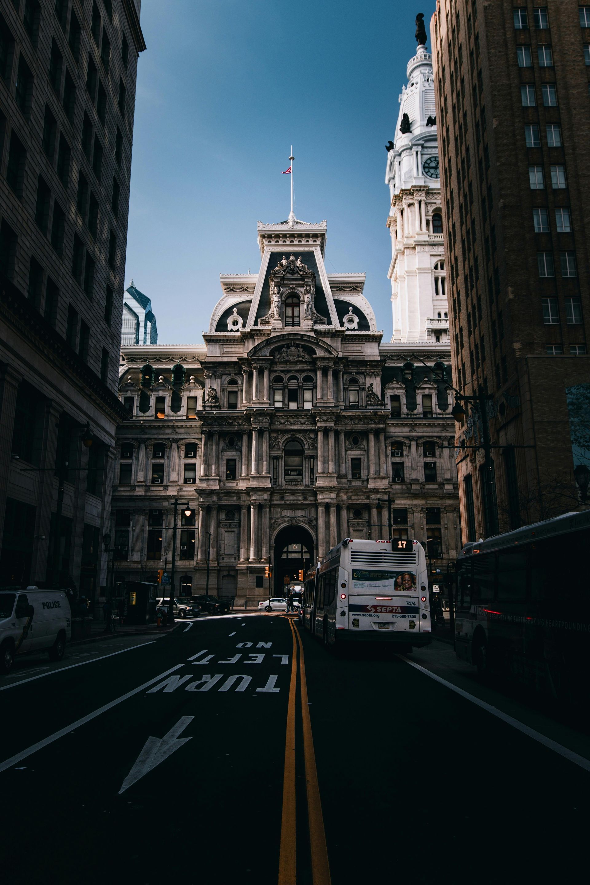 Philadelphia City Hall framed by city buildings. Street view with a white bus and cars.