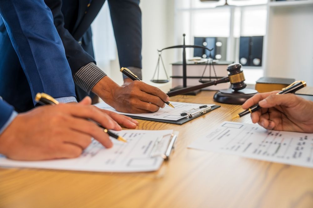 People in suits reviewing documents with pens, scales and gavel on the table.