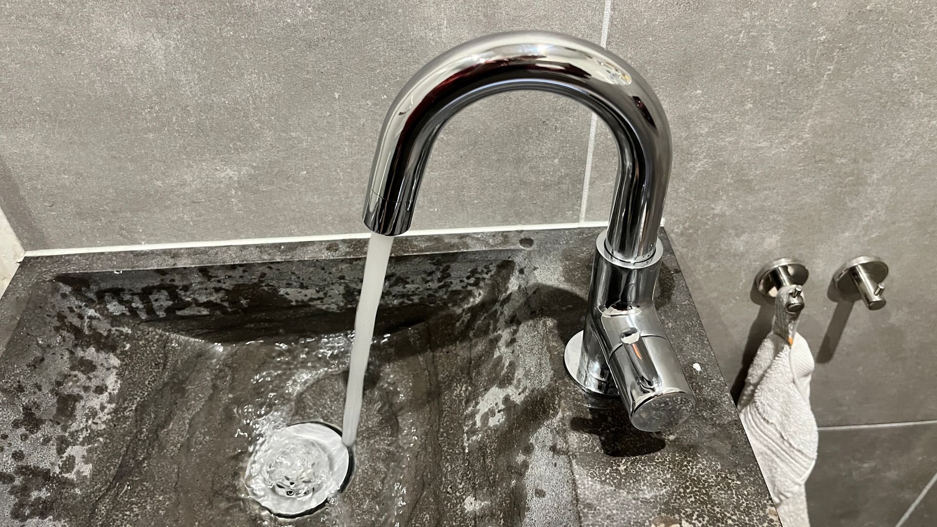 Een wastafel in de badkamer met stromend water uit een kraan.