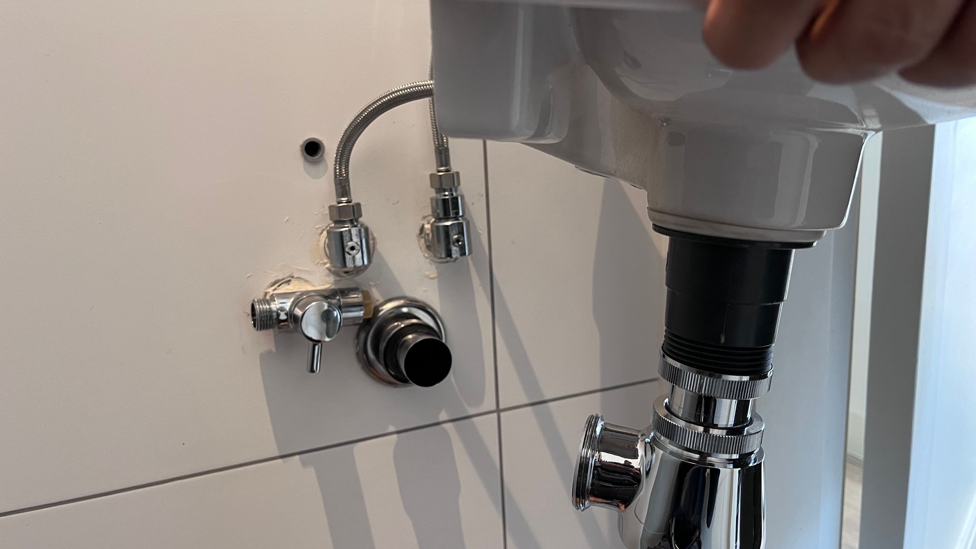 Iemand repareert een wastafel in een badkamer.