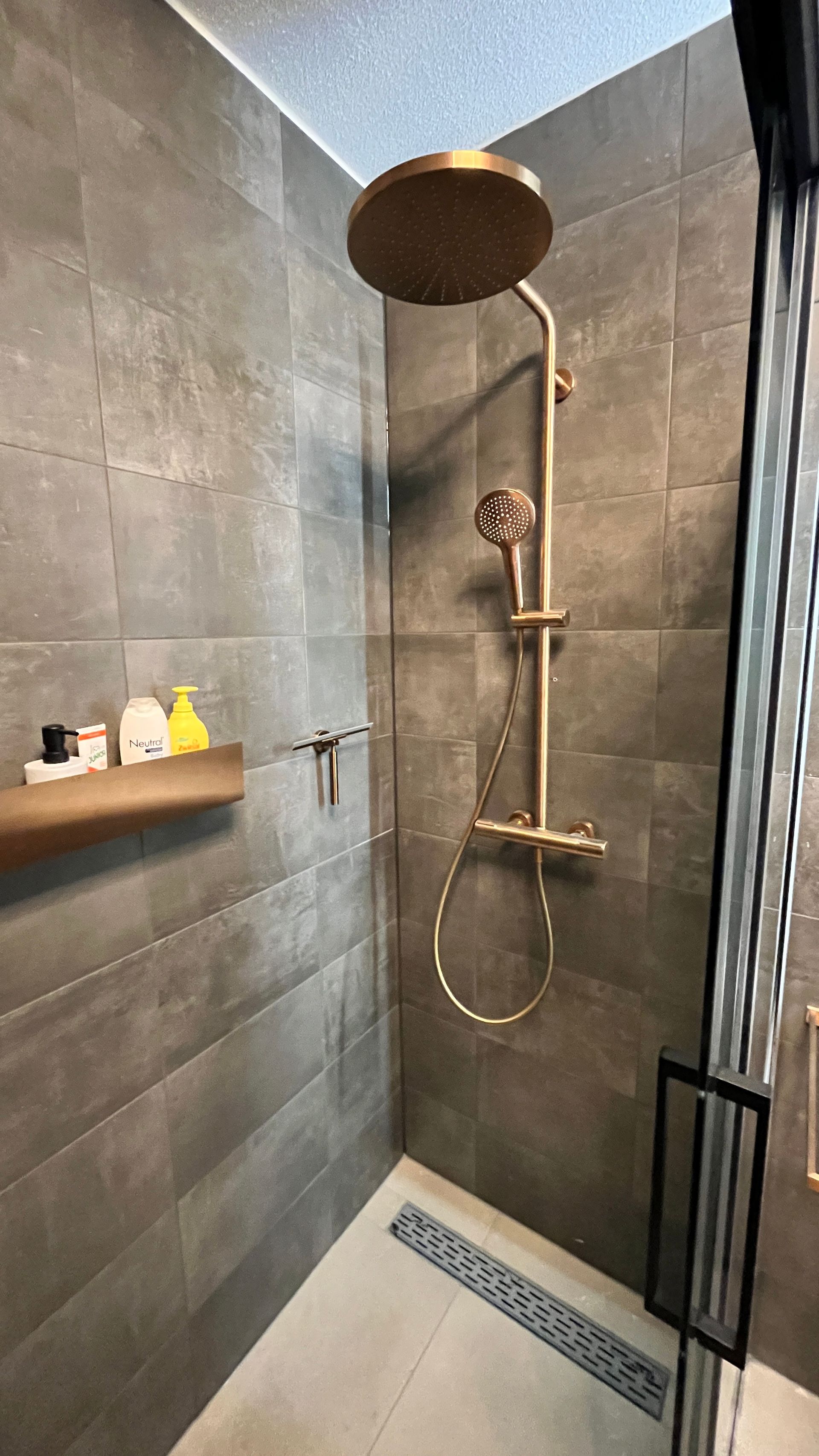 Een douche met een glazen schuifdeur en een douchekop.