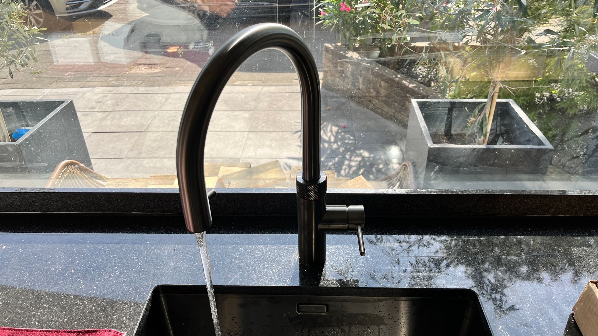 Een gootsteen in de keuken met stromend water uit de kraan en een raam op de achtergrond.