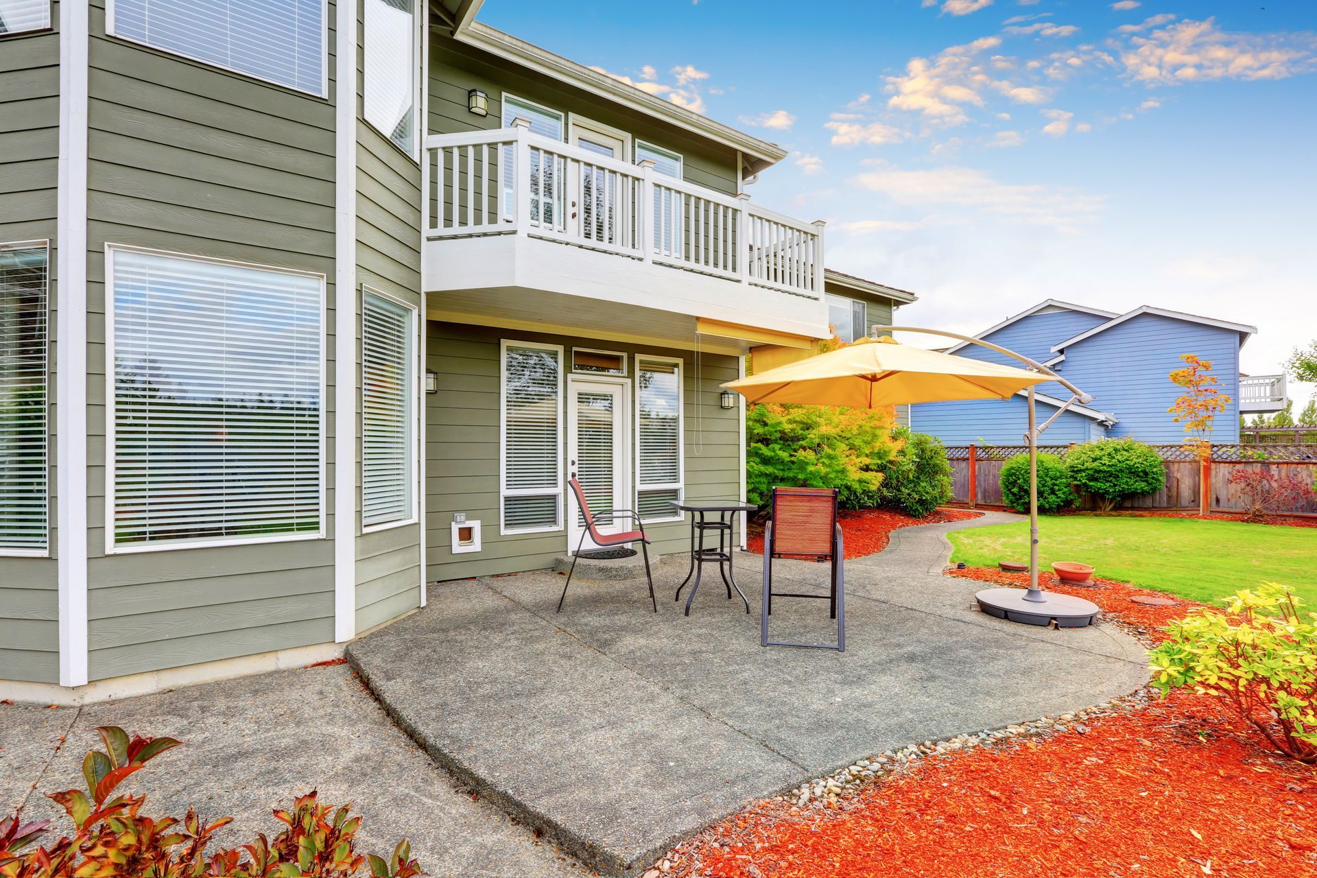 A large house with a patio and umbrella in front of it.