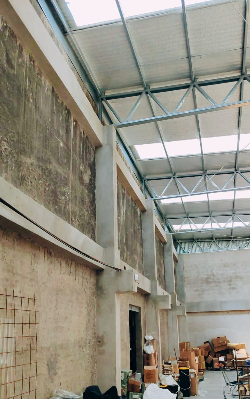 Interior de un almacén con paredes de hormigón, techo de metal y luz solar que entra a raudales por las claraboyas.