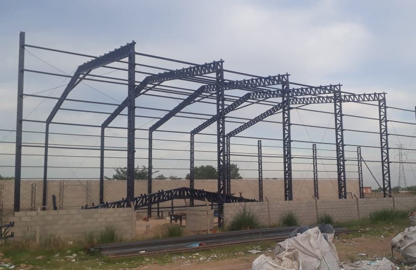 Estructura de acero de un edificio en construcción, metal oscuro contra un cielo nublado.