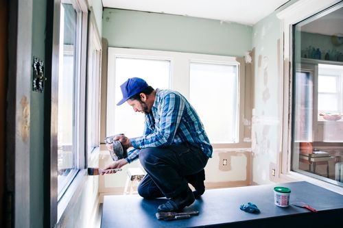 Man painting interior window sill at home.